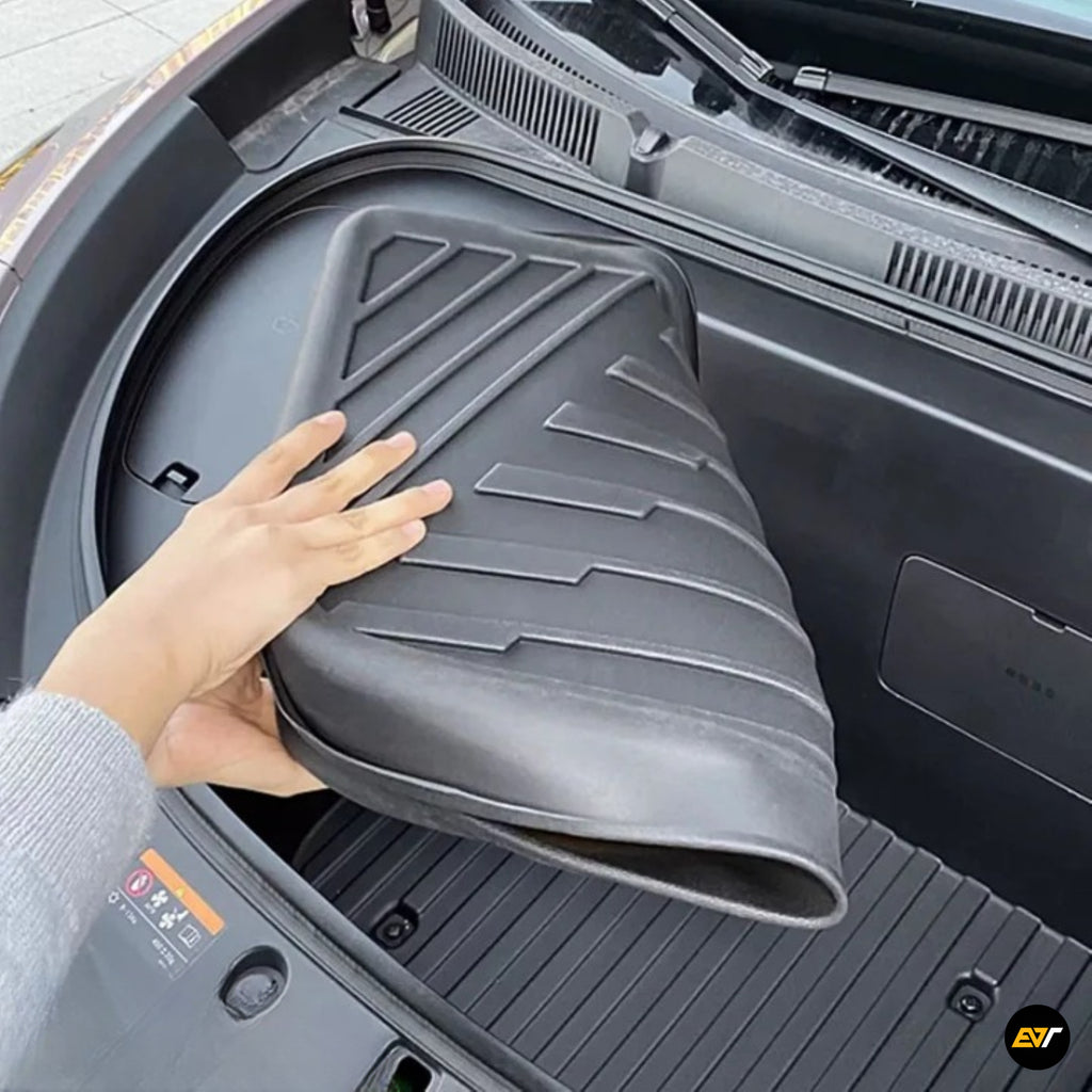 Black moulded front boot liner being placed inside an electric vehicle frunk for added cargo area protection