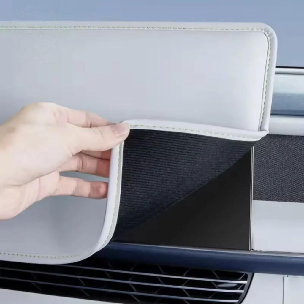 Hand holding a white protective cover showing soft inner lining designed for a car navigation screen accessory
