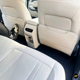 Cream leather rear car interior with perforated seat, seatback storage pockets, rear air vents and centre console control panel
