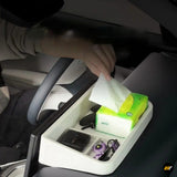 White car centre console organiser with tissue box, multiple compartments and small personal items inside a vehicle interior