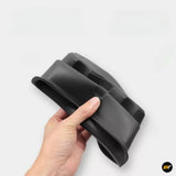 Hand holding a black moulded plastic automotive accessory with curved channels and raised mounting sections