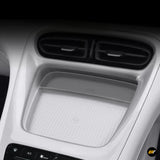 Electric vehicle centre console with twin air vents and a ribbed wireless charging tray beneath them