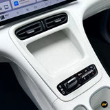 White car centre console with dual air vents textured storage tray and electronic gear selector