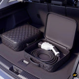 Portable electric vehicle charging cable in an open protective case beside a quilted storage case in a car boot