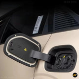 Beige electric car with open charging port, dual socket connector housing and hinged black protective cover against the bodywork