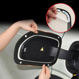 Black electric vehicle charging port cover being fitted with adhesive trim and a visible high voltage warning symbol