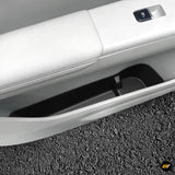 White vehicle door panel with black textured storage compartment insert and window switch detail for electric vehicle interior alcove