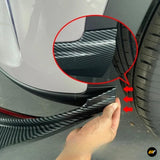 Hand fitting carbon fibre effect bumper trim beside a vehicle wheel arch and tyre, with red arrows highlighting the installation area