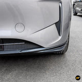 Close-up of a silver car front bumper with carbon fibre-style lower lip, side air vent and wheel detail