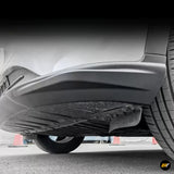Close-up of a black vehicle side step and underbody protection beside the rear tyre, showing rugged textured detailing and ground clearance