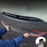 Black and red vehicle front grille trim with mounting clips positioned below a white bumper panel