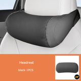 Black perforated vehicle seat headrest cushion fitted to a white leather car seat for added neck support