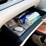 Open car dashboard storage compartment with drinks, tissues, keys and personal essentials inside a modern vehicle interior