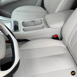Light grey car interior with perforated front seats, centre console, cup holders and steering wheel detail