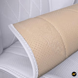 Close up of a beige perforated padded cover with embossed floral detailing and white stitched edging on a quilted surface