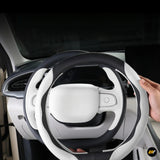 White and black steering wheel cover being fitted inside a modern car interior for a stylish and comfortable driving grip