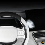 Close-up of a black and white car steering wheel, dashboard touchscreen and central air vent in a modern interior