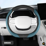 Black and teal steering wheel cover fitted to a white car interior with dashboard and controls visible