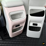 Pink and white rear car centre console panels with storage compartments, a charging port and black padded tray areas