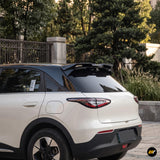 White SUV with a black rear roof spoiler and tinted rear window parked beside a landscaped driveway