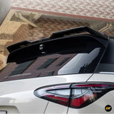 Gloss black rear roof spoiler fitted to a white car above the rear windscreen and tail light
