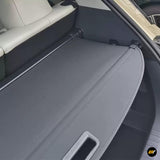 Grey retractable boot load cover fitted inside a vehicle luggage compartment with integrated pull handle