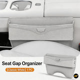 Classic white car seat gap organiser with front storage pocket and lower phone slot beside a vehicle centre console