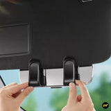 Hands adjusting two black mounting clips on the underside of a vehicle accessory against a blurred outdoor background