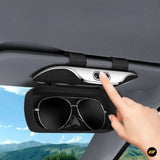 Black car sun visor sunglasses holder with push button, mounted inside a vehicle and storing a pair of sunglasses