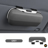 Grey car sun visor accessory with silver trim, central charging port and two black mounting straps shown in close-up