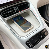 Wireless smartphone charging tray in a car centre console beside the gear selector, shown with a phone resting on the charging surface