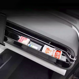 Open car glove compartment with glossy black interior and various packaged food items stored inside