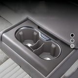 Close-up of a rear armrest integrated cup holder with dual compartments in grey leather upholstery, designed for electric vehicle interiors.