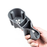 Hand holding a grey plastic rear armrest cup holder with multiple compartments for an electric vehicle accessory.
