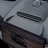 Interior close-up of a grey storage box behind navigation screen with air vent and speaker in electric vehicle dashboard
