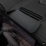 Black textured storage box mounted behind navigation screen with integrated card slot in electric car interior