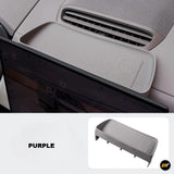 Purple storage tray mounted behind navigation screen in electric vehicle interior with non-slip surface and logo detail.
