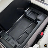 Electric vehicle centre console armrest storage box with removable black organiser tray and sliding cover panel