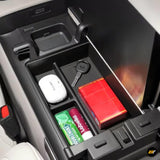 Open centre console armrest storage box in electric vehicle with organisers holding key, gum, and small accessories
