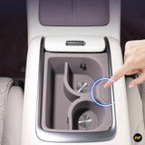 Centre console cup holder insert with two cup slots and a control button in a light-coloured electric vehicle interior