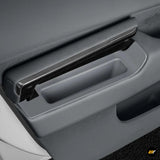Close-up of a black storage box integrated into an electric vehicle door panel with sleek, modern design.