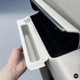 Hand opening white hidden storage compartment in electric vehicle door panel with sleek design and black interior lining