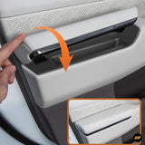 Person opening hidden storage compartment in light grey car door panel with perforated design and black trim details