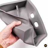 Hand holding flexible grey silicone storage box with divided compartments and two mounting slots inside.