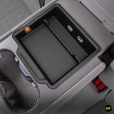 Black rear seat armrest storage box with USB ports and cup holder in an electric vehicle interior